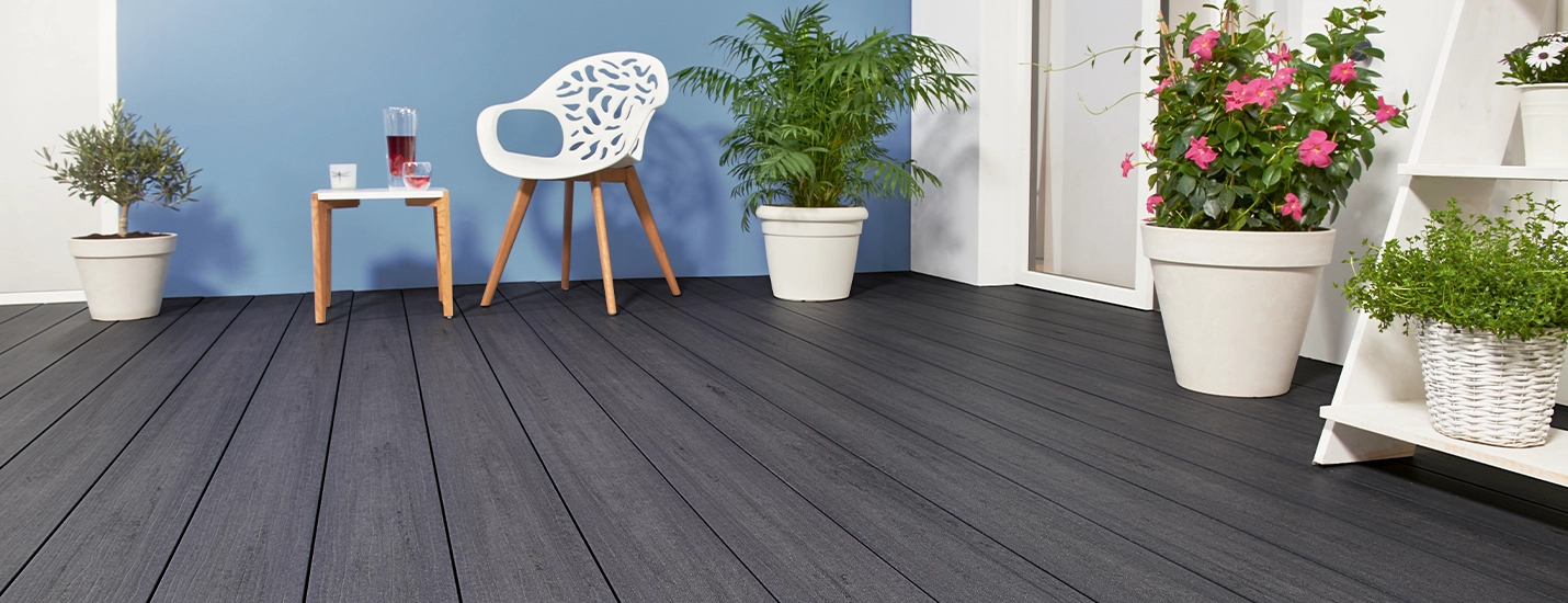 Terrasse mit dunkelgrauen Dielen, weißen Pflanzkübeln und moderner Sitzgruppe.