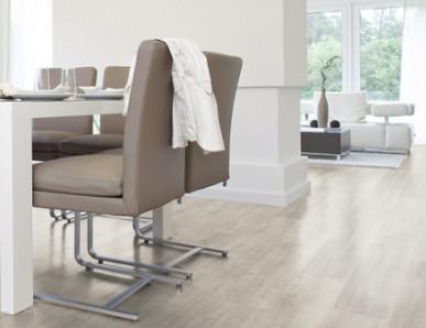 Der Boden im Esszimmer ist mit hellem Vinyl belegt. Dazu gibt es einen großen Esstisch und passende Stühle.