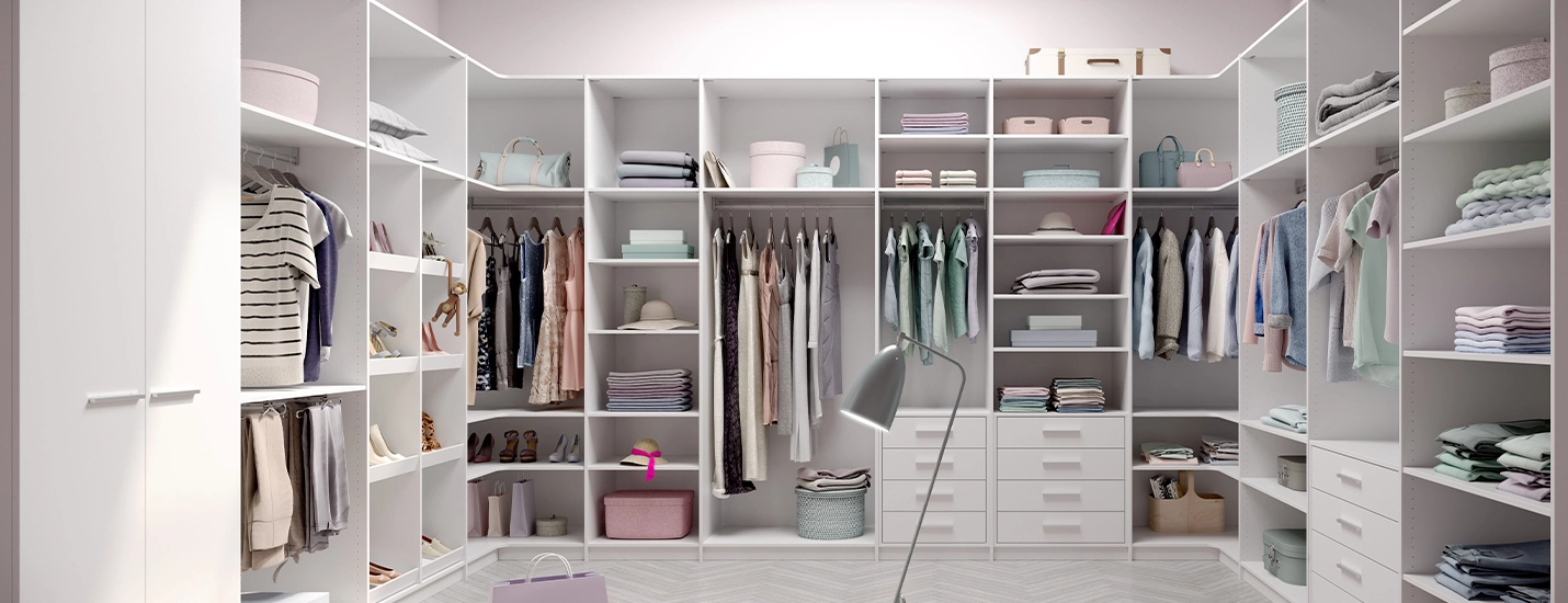 Großzügiger begehbarer Kleiderschrank mit weißen Regalen, Schubladen und ordentlich sortierter Kleidung.