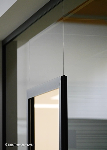 Schmale Glas-Schiebetür mit schwarzem Metallrahmen und dezenter Grifföffnung.