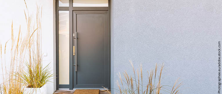 Graphitfarbene Eingangstür eines Hauses mit seitlichen und oberen Glaselementen für zusätzliches Licht.