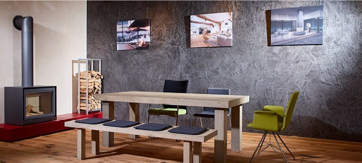 Essbereich mit Holztisch, Kaminofen und dekorativer Wandgestaltung aus Steinputz.