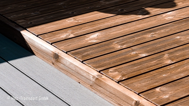 Große Dachterrasse mit hellen Holzdielen und horizontaler Brüstung.