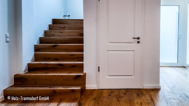 Helle Diele mit natürlicher Eichendiele, moderner weißer Tür und durchgehendem Parkett bis zum Treppenaufgang.