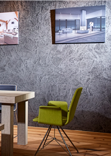 Essbereich mit Holztisch, Kaminofen und dekorativer Wandgestaltung aus Steinputz.