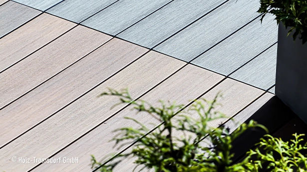Zweifarbige Terrassendielen in Grau und Beige neben Pflanzkübel, attraktive Präsentation von Terrassenbelag und Farbauswahl.