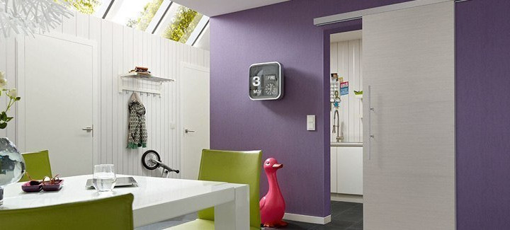 Modern eingerichtetes Esszimmer, violette Wand mit heller Schiebetür zum Durchgang zur Küche