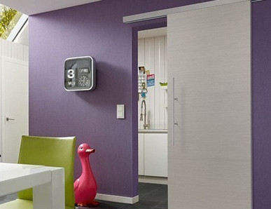 Modern eingerichtetes Esszimmer, violette Wand mit heller Schiebetür zum Durchgang zur Küche