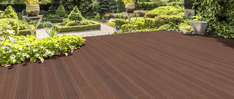 Dunkle Bambusterrasse, dahinter ein weitläufiger grüner Garten.