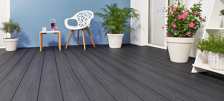 Terrasse mit dunkelgrauen Dielen, weißen Pflanzkübeln und moderner Sitzgruppe.