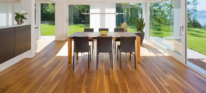 Die Küche ist mit massivem Boden ausgelegt. In der Mitte steht ein massiver Tisch mit Stühlen, und durch die Glasfenster sieht man den Ausgang zur Terrasse und zum Garten.