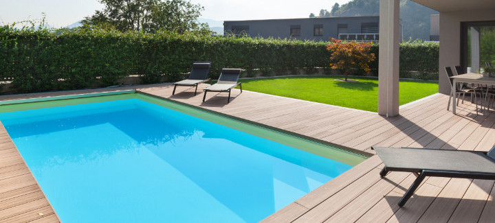 Terrassendielen umgeben einen Swimmingpool im Garten.